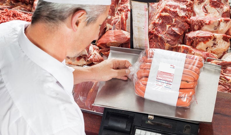 Butcher using meat scale to price and label meat