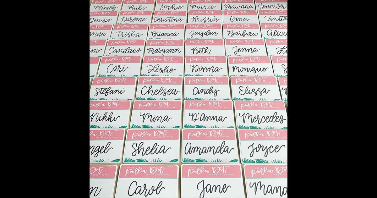 Name tag example, pulled from @taylorofalltrades: branded name tag stickers with pink headers, cursive names, and green floral accents